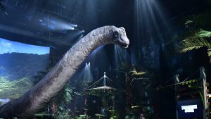 A dinosaur towers above the audience at Jurassic World: The Exhibition