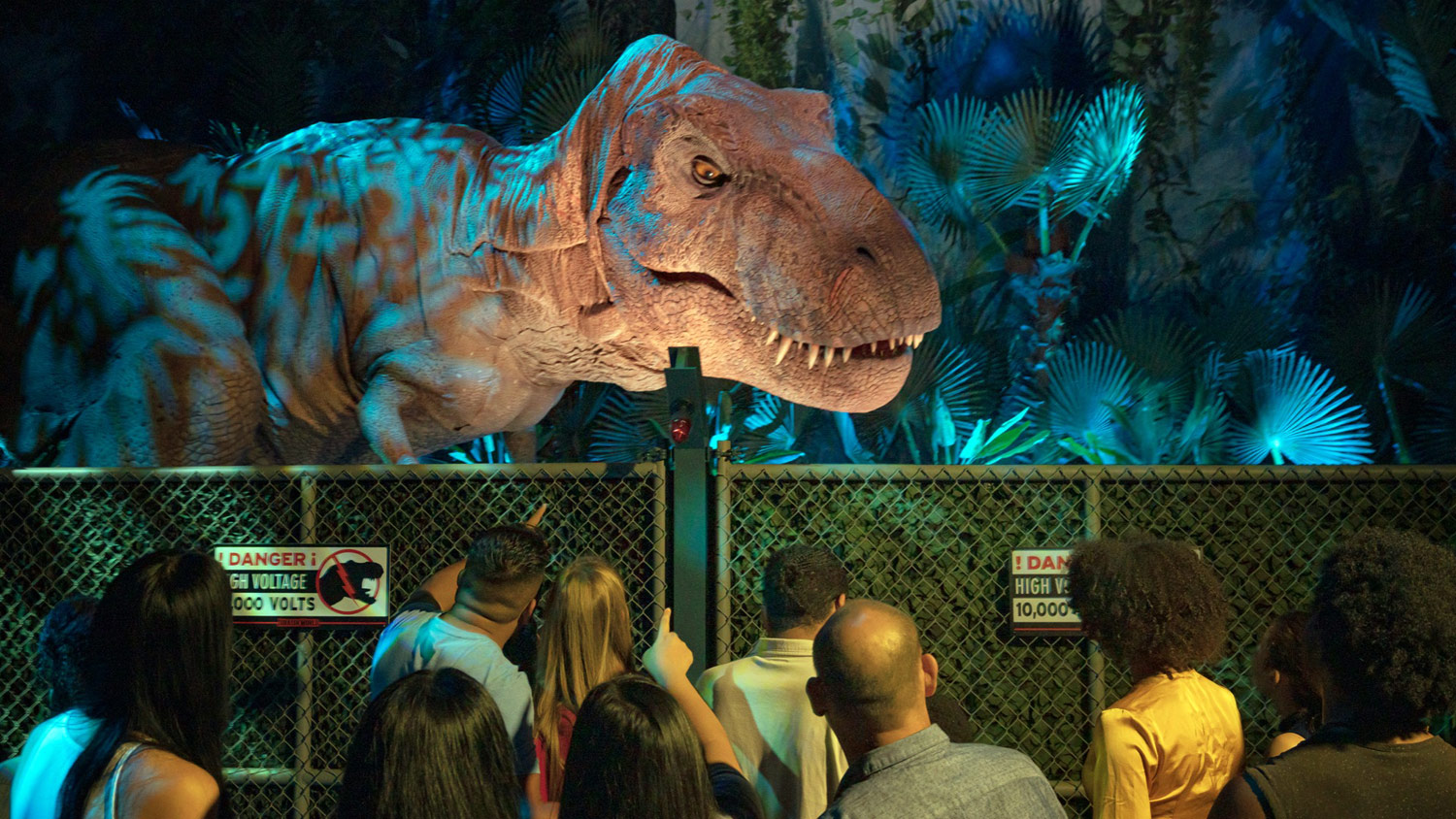 In a darkened passage, a dinosaur peers at the crowd at Jurassic World: The Exhibition